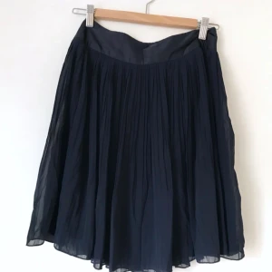  - Superfin mörkblå kjol i två lager med underkjol och överdel i plisserad chiffong. Någon form av siden i midjan, dragkedja i sidan. Passar både till fest & vardag! H&M, storlek 36. Fint skick!