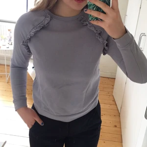  - Grå/lila aktig sweatshirt med volanger upptill, lite kortare i modellen. Sparsamt använd!