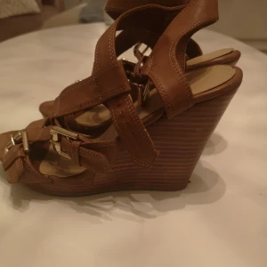  - Bruna kilklackar med gulddetaljer      Bruna kilklackar med gulddetaljer   knappt använda 