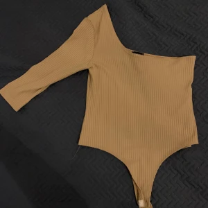 Body från Pretty Little thing - Denna beige bodysuit är i mycket bra skicka, den är endast använd ett enstaka gånger. Den är storlek 12/42 men skulle säga att den passar M/L. 