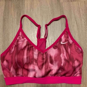  - Sport-bh med inlägg från Nike. Rosa i Storlek M. Använd ett fåtal gånger, i gott skick. Aningen liten i storleken. Köparen står för frakt.