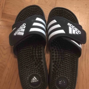  - Ett par adidas tofflor från USA. 