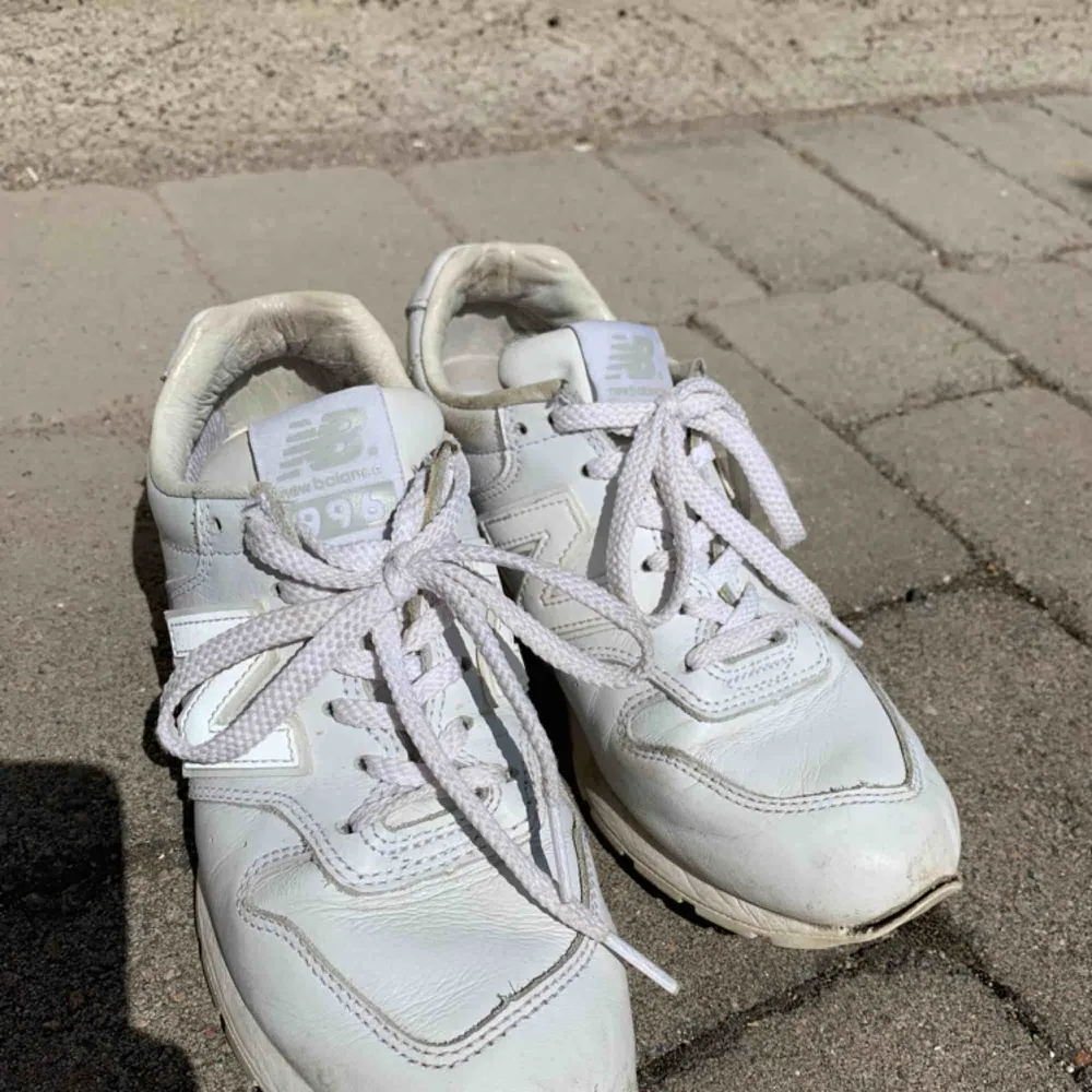 Ett par vita sneakers i läder från New Balance. Köpta för ett tag sedan men tyvärr för stora för mig så sparsamt använda. Lite slitna fram och på sidorna men annars väldigt fina! Modell 996. . Skor.