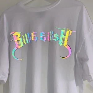 Billie Eilish x bershka t-shirt strl M - Tröja från billie eilish kollektion med bershka. Använd men i fint skick. Oversized, texten är reflective men det syns inte när det är dåligt ljus, därav att första bilden är tagen med blixt för att det ska synas.  nypris är 199kr