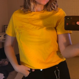Gul t-shirt med detalj  - En gullig gul t-shirt med ett fint tryck i rött. Tröjan är i bra skick eftersom jag aldrig har burit den men har tyvärr inte kvar prislappen! Frakten ingår inte i priset
