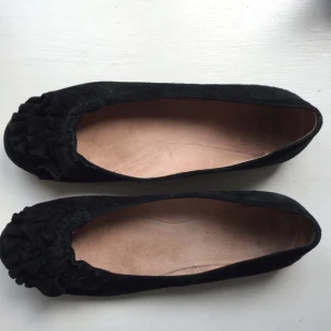  - Svarta ballerina i mocka med volanger framtill. Fina, säljes pga för liten storlek

Black ballerina flats in suede material, selling because they are too small but still in good shape! 