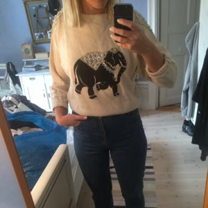  - Ljus stickad tröja med snyggt elefanttryck och glitterdetaljer 