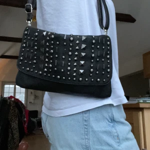 En svart väska med nitar - Skitcool svart väska med nitar. Köpte för 520 kr second hand men vet ej riktigt vilket märke det är.