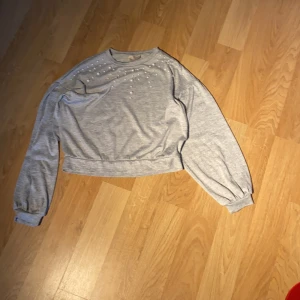 Grå tröja st.xxs - Grå tröja från H&M/Divided i xxs skulle nog passa xs/s också.Andvänd ca.2 ggr. Väldigt fint skick, säljer p.g.a att den in kommer till andvändning. De är också små silverpärlor på övre delen av tröjan!