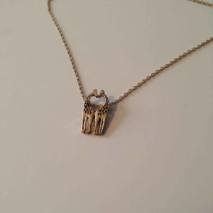  - Guldigt halsband med två giraffer. Kan ställas in på flera längder. 