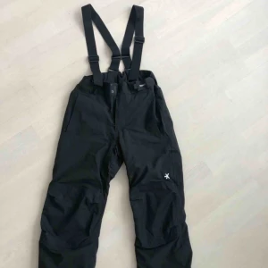  - Svarta skidbyxor från Everest Adv i strlk 164. Avtagbara hängslen samt justerbar midja och benslut. Byxorna är i väldigt gott skick med måttlig användning.