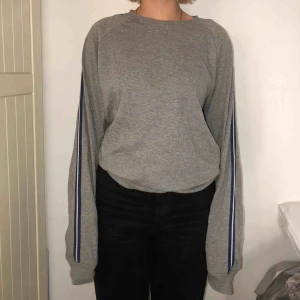  - Grå longsleeve från Lindbergh White i strl M. Har blå/vit rand längst ärmarna. Passar perfekt till ett par ljusa jeans nu i sommar! Använd 2 ggr. Köparen står för ev frakt!🌼