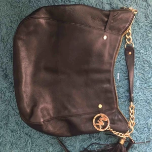  - Nästintill oanvänd Michael Kors Väska i fint skick. Bra med fack och inredning, äkta svart läder.  Bred: 35 cm Högd: 30 cm 