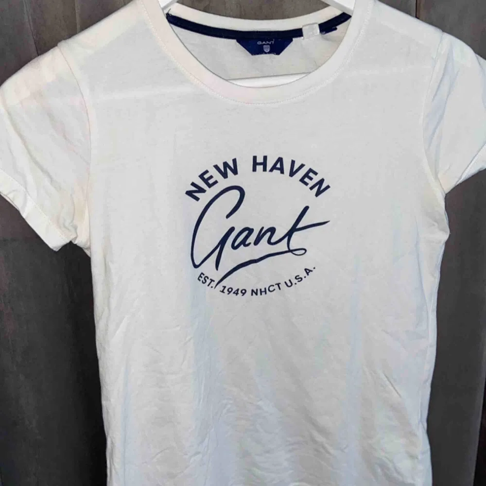 En vit t-shirt med blått tryck på bröstet/magen. Den är använd flera gånger och är suuperskön. Fungerar även för dig med storlek small. Nypris 399kr . T-shirts.