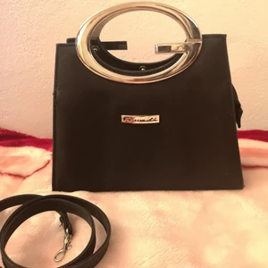 handväska  - Liten men rymlig cool handväska i svart textil/krom i fint skick. Storlek ca 20x20 cm. 3+1 fack inuti. Axelrem medföljer. Pris 60 kr + ev frakt. Finns i Sthlm/Uppsala.