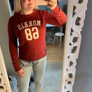 Stickad tjocktröja - Morris - En röd stickad Morris tjocktröja med svarta stickade armbågar. Är köpt som herr tröja i storlek S men jag som är tjej och brukar använda L i tjej kläder får på mig den lite tajt bara. Inköpspris ca. 1000kr. Är i bra skick.