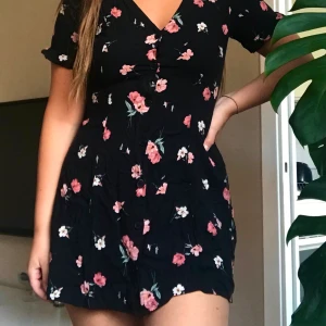 Blommig klänning - En klänning från H&M endast använd 1 gång. Med knappar längs med hela framsidan. Den är i storlek 42 men är suuuuperliten i storleken, skulle säga att den är en XS eller S! Köparen står för frakt 