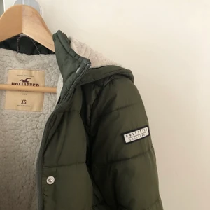 En grön vinterjacka - En grön vinterjacka från Hollister. Den är använd två vintrar av mig. Väldigt varm, med fluffig insida. Dragkedjan på båda fickorna är tyvärr sönder. Den kostade 1000kr i nypris. Skriv gärna till mig om du har frågor eller vill ha fler bilder😊