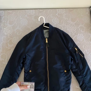 Jacka (bomberjacka) - Alpha industrier mörkblå bomberjacka , strolek L . De är mindre i storleken . Har M och de passar mig.  Använd den 2 veckor Max . Original pris ungefär 1500 ,Ny pris 300kr.