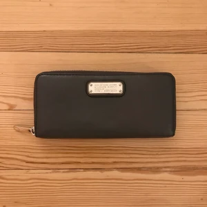 Plånbok Marc by Marc Jacobs - Seeeeevinsnygg och rymlig plånbok i grått skinn med silverdetaljer från Marc by Marc Jacobs. Köpt för ett par år sen i New York. Liksom lyxig kompakt men man får plats med allt?? Sparsamt använd och i nyskick förutom repa på loggan i metall (se bild 3). 450 kr inkl frakt!