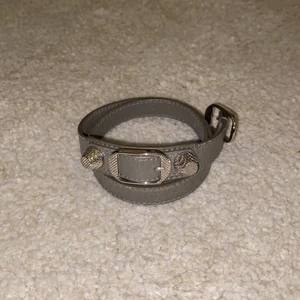 Balenciaga armband  - Grått armband från Balenziaga som man snurrar runt handleden! Knappt använt pågrund av för liten storlek. Strlk.S! Köpt på Nathalie schuterman och går ej att köpa längre! 