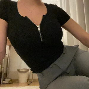Svart topp med dragkedja - Svart ribbat topp med en silvrig dragkedja, väldigt figursydd, relativt stretchig, storlek XS ❤️❤️