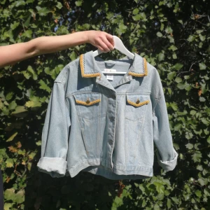 Vintage jeansjacka - Jeansjacka med broderi av Time Square på ryggen. Storleken är L men är snygg oversized också! Frakt ingår i priset. 