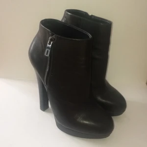 Högklackade stövletter i svart läder - Använt ett fåtal gånger och är i jättefint skick, inga anmärkningar. Hög klack med platå framtill. Snygg detalj med dragkedja på utsidan. Priset är inklusive frakt, skickas med postens lätt spårvagn 63kr alt. Hämtas på Södermalm.