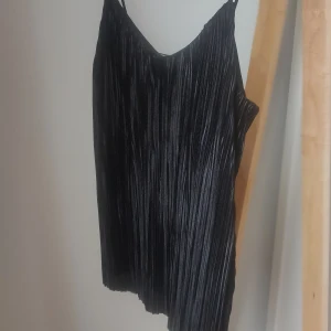 Svart plisserat linne, oanvänt. - Svart plisserat linne i glansigt material. Oanvänd med prislappen kvar. Köpt förra sommaren men säljes då det är för litet för mig. Kan skickas, då står jag för frakten. 