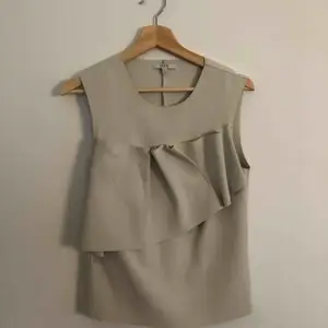 House of Dagmar topp Sparsamt använd.  Vit/beige topp utan ärmar med dekorativ detalj på bröstet.   Storlek 36 