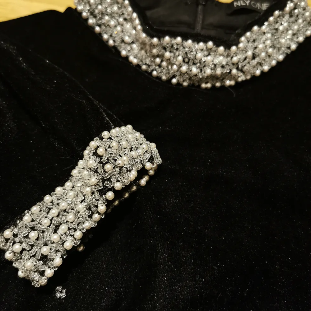 Fin festklänning i sammetsliknande tyg med pärldetaljer vid halslinning och ärmslut. Använd endast 1 gång, i fint skick. . Klänningar.