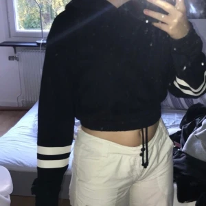 Croppad hoodie - Marinblå croppad hoodie med två vita ränder runt ärmarna i storlek m. Från h&m. Resår i midja och handleder. Passar även folk med storlek s. Säljer pga att jag knappt använder den längre. 