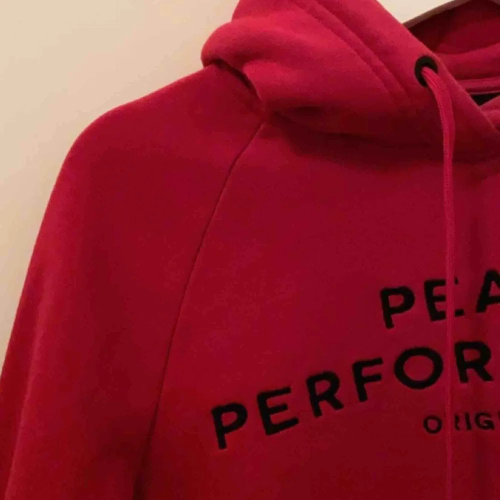 Väldigt fin hallonröd hoodie från Peak Performance med svart tryck, sparsamt använd och i väldigt bra skick. Storlek XS.. Hoodies.