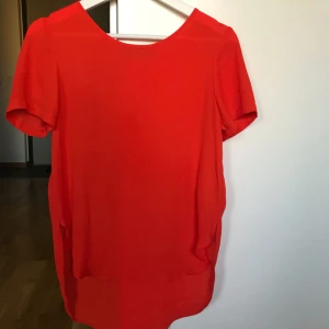 - T-shirt-blus från Bikbok. Använd ett par gånger. Liten slits och något längre bak. Underbar tomatröd färg. Frakt 35:-