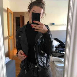  - En svart snygg skinnjacka(fejk). 2 ytterfickor. Köparen står för frakten.