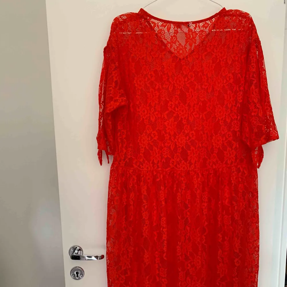 Halvlång klänning, röd halvt genomskinlig med knyt på armarna.   Porto betalas av köparen. . Klänningar.