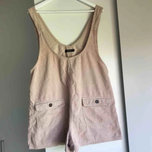  - Gullig playsuit i Manchester. Funktionella fickor på framsidan och dekorativa fickor på baksidan Gammalrosa/ljusrosa/beige i färgen. Inköpt i Nya Zeeland!   Upphämtas i Gbg / köparen står för frakten 