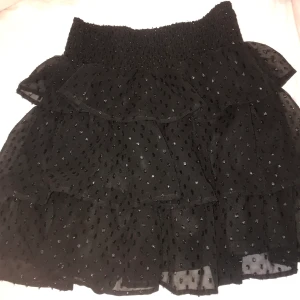 Kjol med volang - Svart glittrig super söt kjol från Vero Moda. Använd en gång. 😊 Storlek 38 men passar mig som har 36 vanligtvis.
