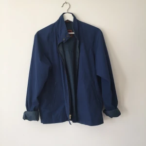  - Klarblå täckjacka med fickor och hög krage