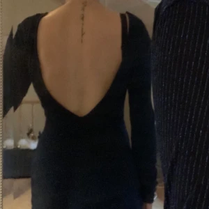 Tajt klänning - Tajt långärmad klänning i storlek xs. Öppen / djup rygg. Svart blå och glittrig. 