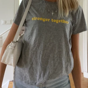 Grå T-shirt med tryck - Jag säljer denna gråa T-shirt med ett gult tryck på bröstet. Den är från ginatricot och är köpt för 129kr. Den är sparsamt använd men i väldigt fint skick. Jag säljer den för 60kr+frakt(bra pris)⚡️hör av dig vid intresse eller frågor🤍