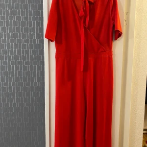 Jumpsuit från pieces stl. XL - En helröd jumpsuit som är halvkort i benen. Har används några gånger och har en liten fläck som syns på sista bilden. (Frakt tillkommer ) 