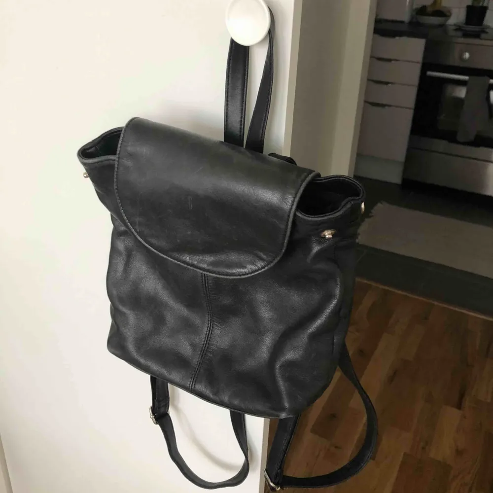 En svart liten väska med ytterfack och innerfack, i fint skick.  Spännbara band. . Väskor.