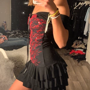 Klänning  - Snygg svart klänning me röda detaljer på fram sidan
