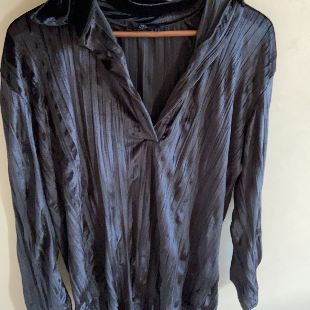 Säljer denna snygga velour-klänning i svart med djup v-ringning och krage. Den är så blank och skiner så den upplevs glittrig. Hänger sjukt snyggt på kroppen och är i fint skick. Passar både med som utan något i midjan och har själv både använt med något under samt utan. En perfekt party-blåsa! . Klänningar.