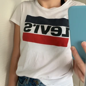Levis t-shirt - Säljer en vit Levis t-shirt som är köpt på Jeansbolaget för ett tag sen för 250kr. Skulle säga att den är stor i storleken för den är XXS, men den passar en som är S och mindre. Skicket är bra då den mest legat bortglömd i min garderob😬. Priset kan diskuteras och köparen står för frakten (: