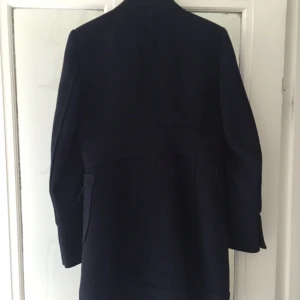  - Mörkblå kappa med svarta knappar i ullblandning. Inköpt på Zara för ca 3 år sedan men i gott skick. Längd 90 cm från krage, bredd 40 cm när den är knäppt. 