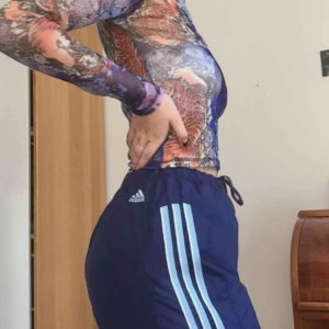  - Mörkblåa Adidas trackpants men ljusblåa streck i storlek M/L. Snörning som går att knyta runt midjan. På bilden sitter de på en S. Slitningar på knäna som jag kan skicka bild på vid intresse! Möts på södermalm. Frakt +50 kr