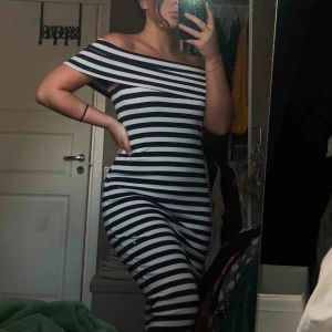  - Stretchig off-shoulder klänning som går under knäna, med vita och marinblå ränder  Frakt ingår