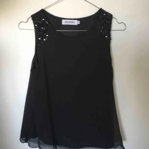  - Svart linne/blus med paljetter på axlarna. Är i storlek XXS men passar även XS. Ingen stretch🌼